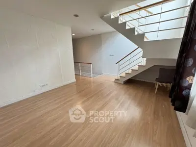 Spacious modern living room with wooden flooring and stylish staircase.