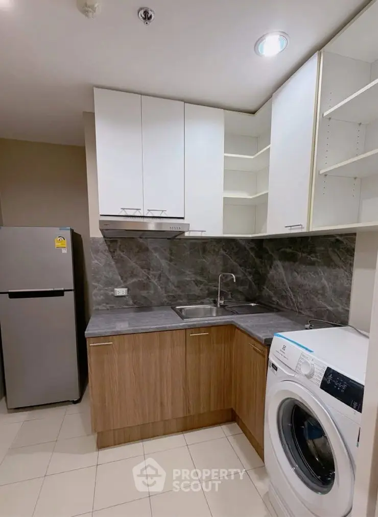 Modern kitchen with sleek cabinets, washing machine, and stainless steel fridge