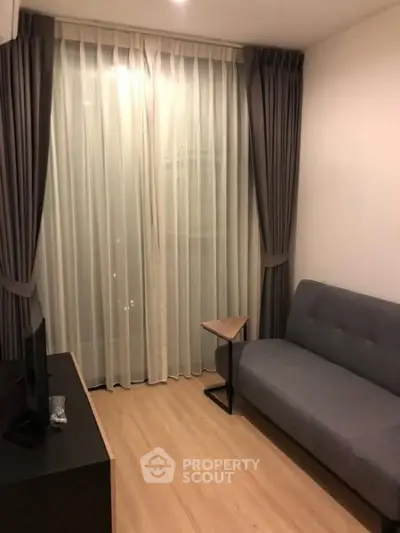Cozy living room with modern gray sofa and elegant floor-to-ceiling curtains.