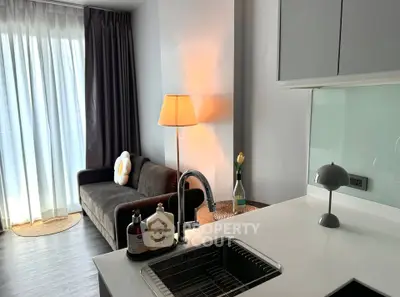 Modern living room with cozy sofa and stylish kitchen area, featuring elegant lighting and sleek design.