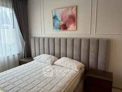 Elegant bedroom with plush headboard and modern art, offering a serene city view through large window.