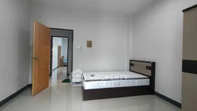 Minimalist bedroom with modern bed and open door leading to hallway.
