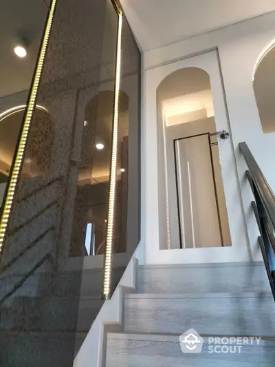 Modern staircase with sleek glass panels and elegant lighting in contemporary home