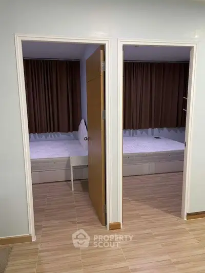 Modern dual bedroom setup with wooden flooring and brown curtains