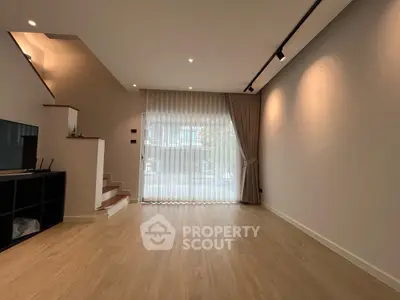 Spacious modern living room with wooden flooring and large window drapes