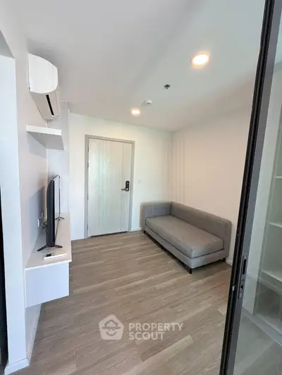 Modern living room with sleek design, featuring a cozy gray sofa, wall-mounted TV, and stylish wooden flooring.