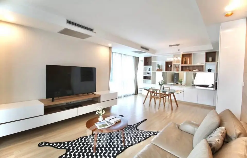Spacious modern living room with sleek furniture and large TV, perfect for relaxation and entertainment.