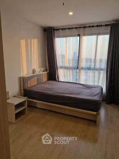 Spacious bedroom with large window and wooden flooring in modern apartment
