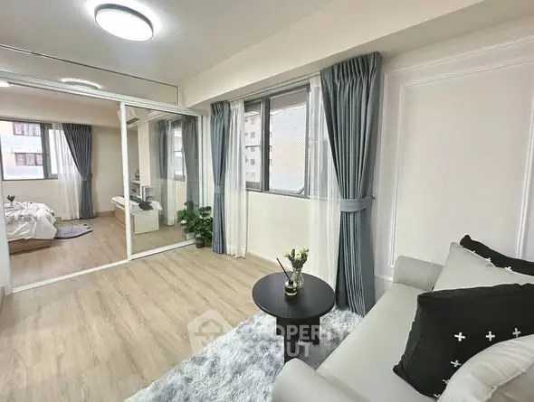 Modern living room with cozy sofa and large windows, adjacent to a stylish bedroom.