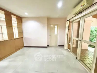 Spacious living room with glass doors leading to a garden view, featuring built-in wooden shelves.