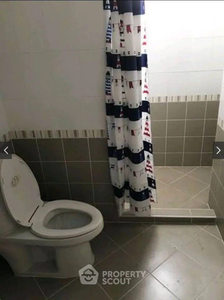 Modern bathroom with tiled floor and nautical-themed shower curtain.