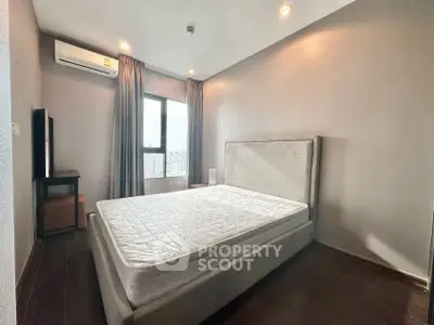 Modern bedroom with large window and city view, featuring a comfortable bed and sleek design.