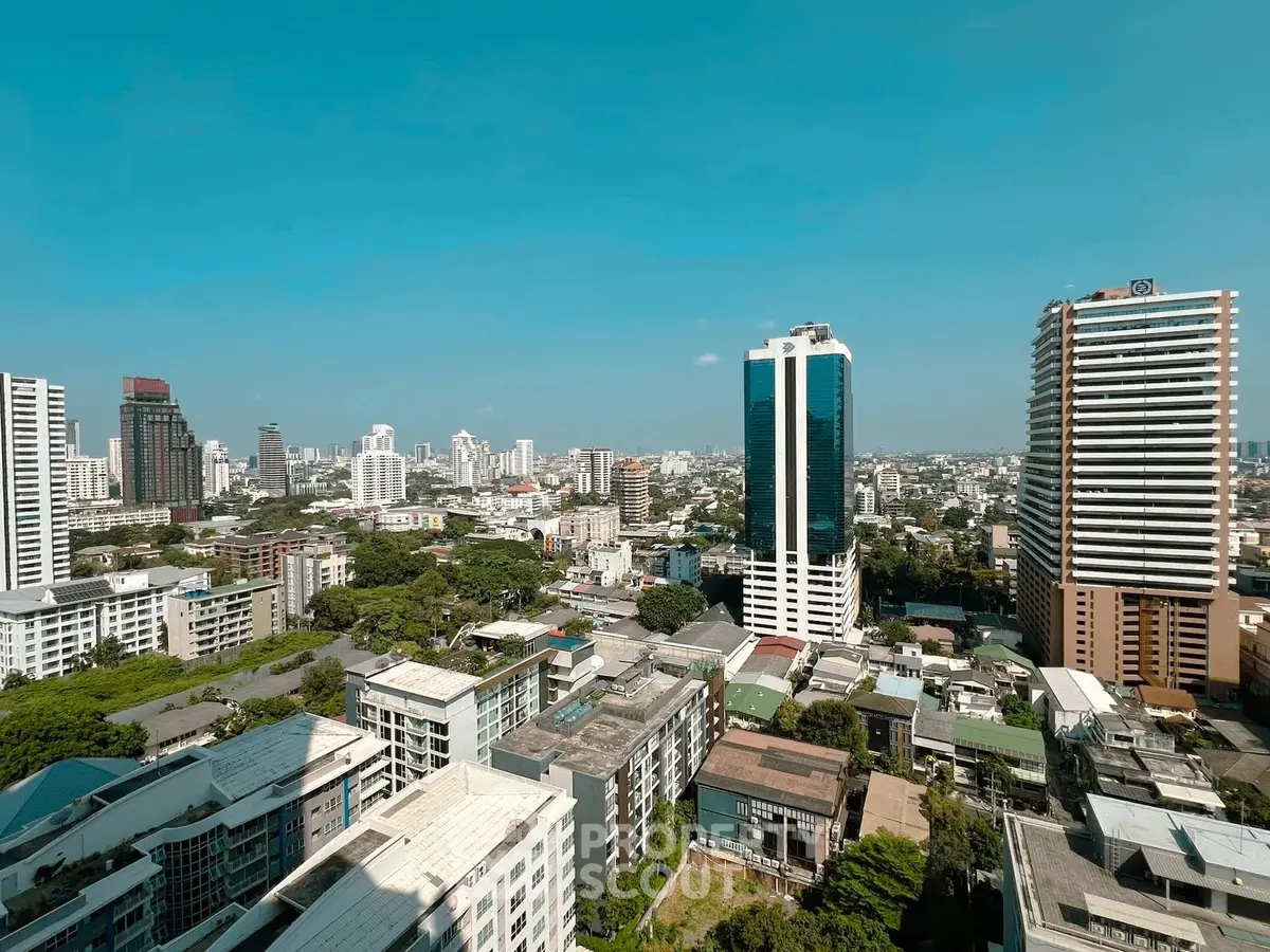 Stunning cityscape view showcasing modern high-rise buildings and lush greenery under a clear blue sky.