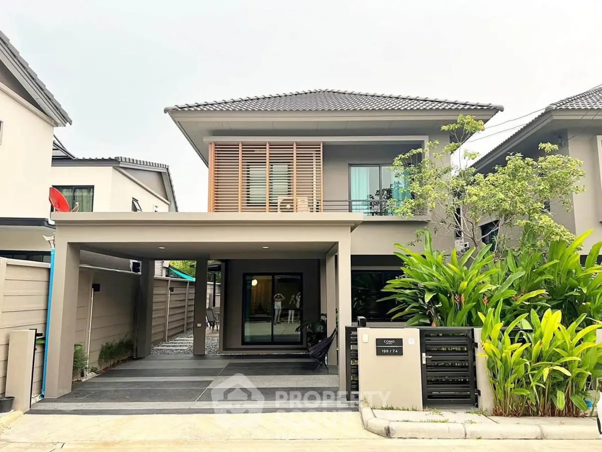 Modern two-story house with sleek design and lush greenery in a suburban neighborhood.