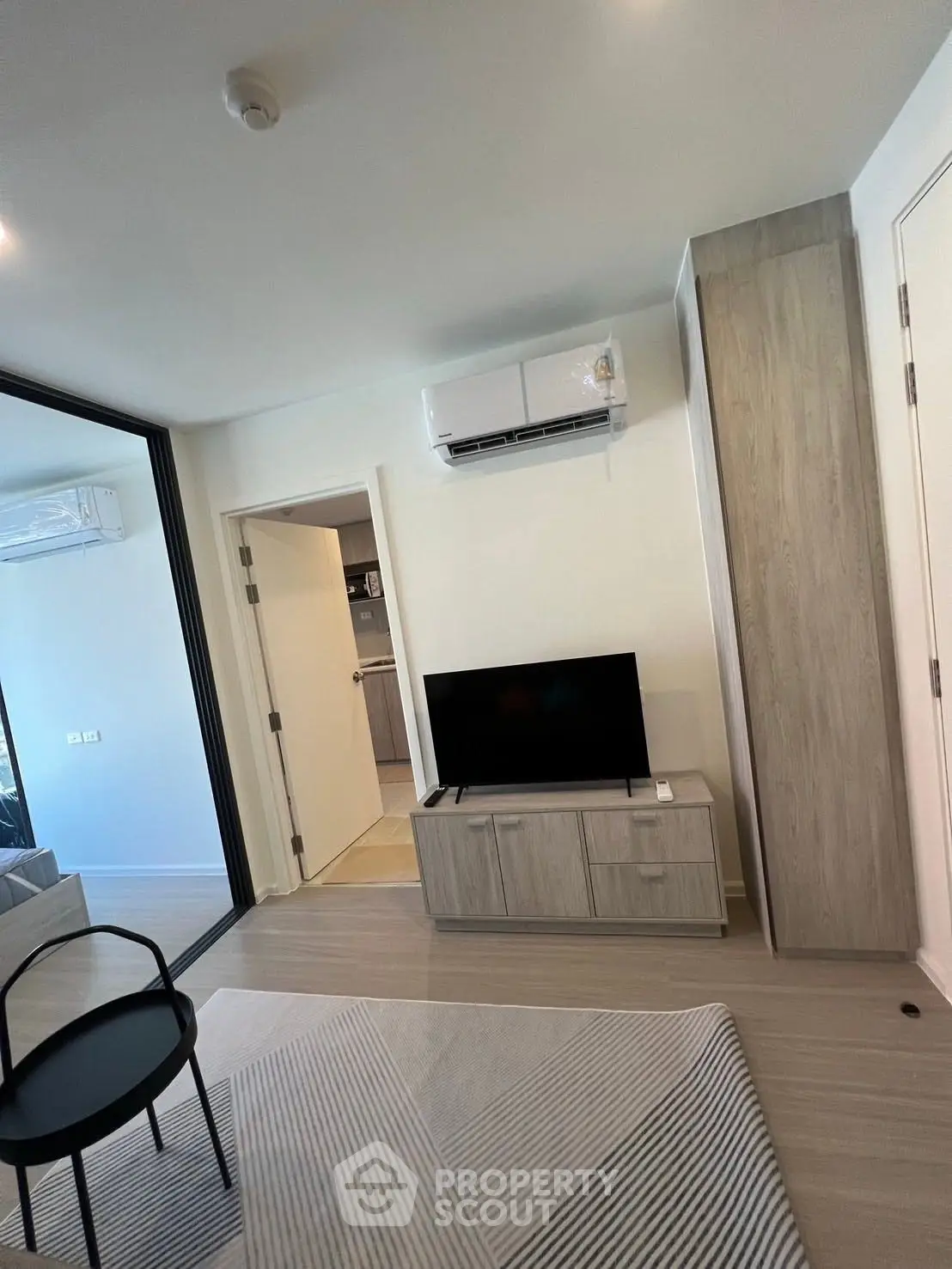 Modern living room with sleek furniture and air conditioning, featuring a minimalist design and neutral tones.