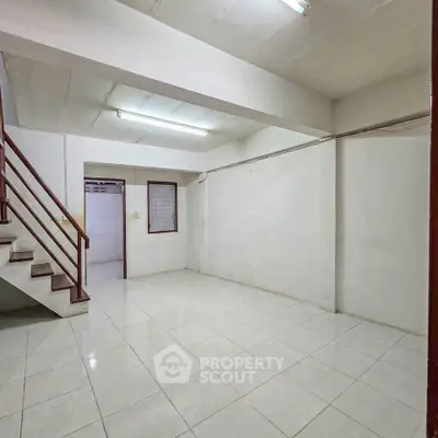 Spacious interior with tiled flooring and staircase, ideal for customization.