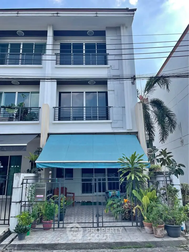Charming three-story townhouse with a cozy front patio and lush greenery.