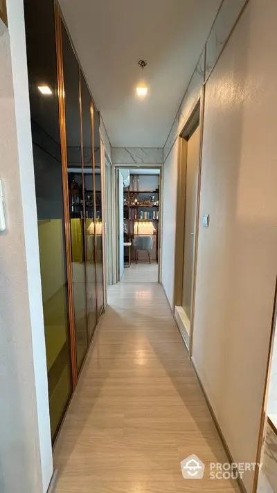 Modern hallway with sleek design and wooden flooring leading to a stylish interior space.