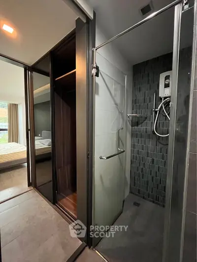 Modern bathroom with glass shower and view into bedroom