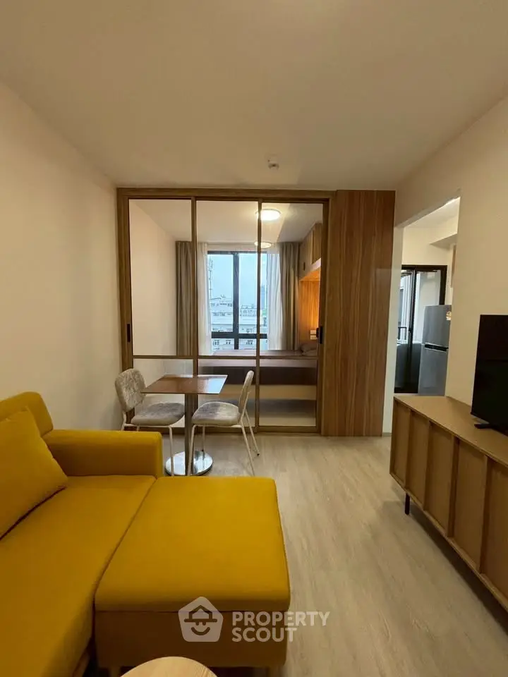 Modern living room with yellow sofa and dining area in open layout apartment.