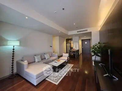Spacious modern living room with elegant decor and open layout, featuring cozy seating and stylish lighting.