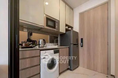 Modern compact kitchen with washing machine and sleek appliances in a stylish apartment.