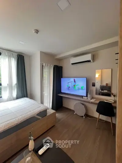 Modern bedroom with stylish decor, large TV, and workspace, perfect for urban living.