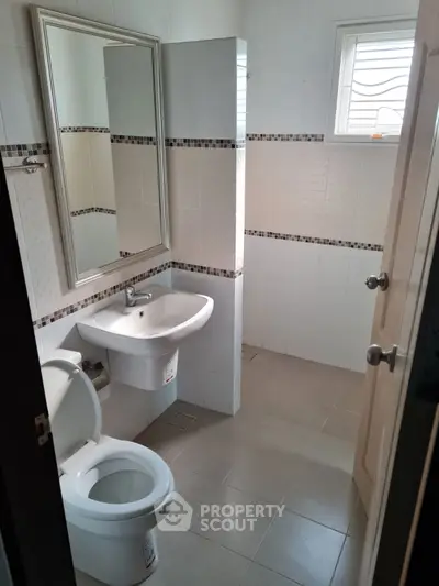 Modern bathroom with sleek fixtures and neutral tiles, featuring a large mirror and natural light.