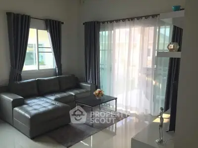 Modern living room with sleek leather sofa and elegant decor, featuring large windows for natural light.