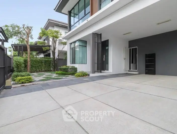 Modern home exterior with spacious driveway and lush garden.