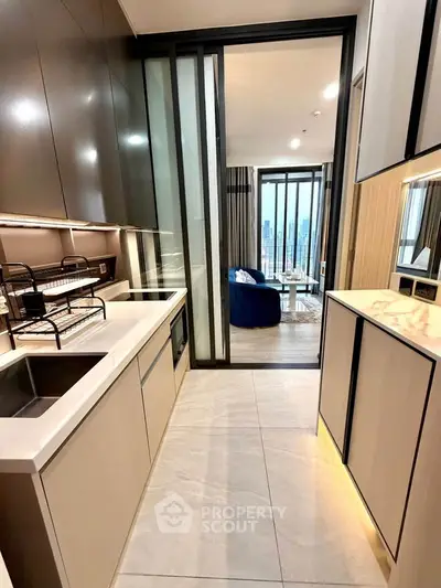 Modern kitchen with sleek cabinetry and open layout leading to a stylish living room with city view.
