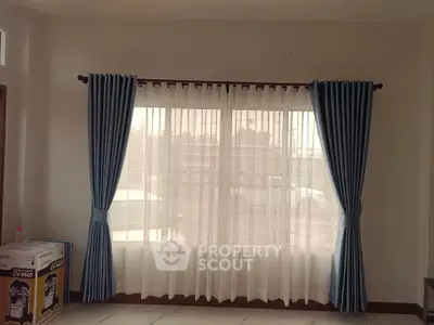 Spacious room with elegant blue curtains and large window, perfect for natural light.