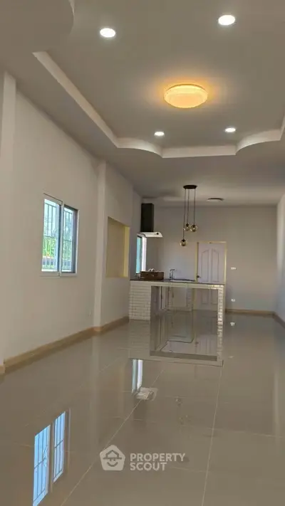 Spacious modern living room with sleek tile flooring and stylish ceiling lights.