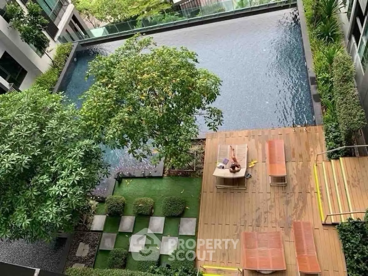 Luxurious condominium pool area with lush greenery and sun loungers, perfect for relaxation.