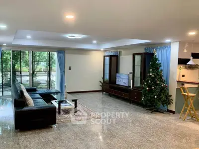 Spacious living room with modern decor and large windows overlooking greenery, perfect for family gatherings.