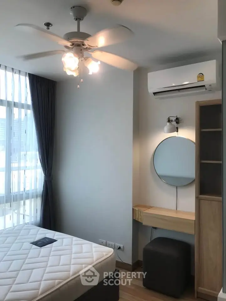 Modern bedroom with natural light, featuring a ceiling fan, air conditioning, and stylish furnishings.