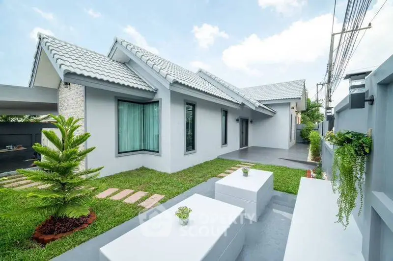 Modern single-story house with landscaped garden and stylish outdoor seating area.