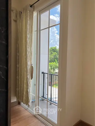 Bright room with glass door leading to a small balcony with scenic view.