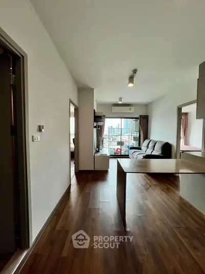 Spacious modern living room with wooden flooring and city view, perfect for urban living.