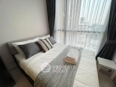 Modern bedroom with city view, featuring elegant decor and large windows for natural light.