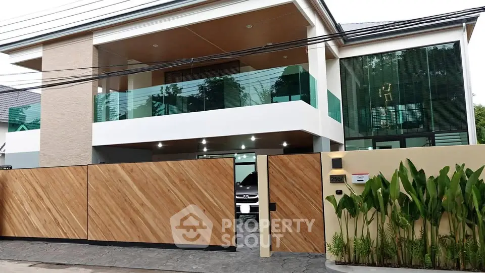 Modern two-story house with wooden gate and lush greenery