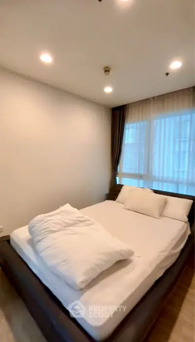 Cozy bedroom with modern lighting and large window for natural light.