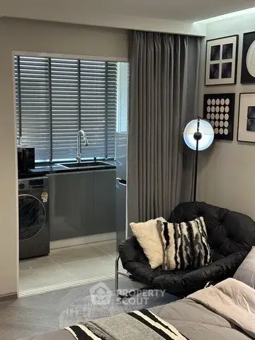 Modern studio apartment with cozy living area and compact kitchen featuring a washing machine.