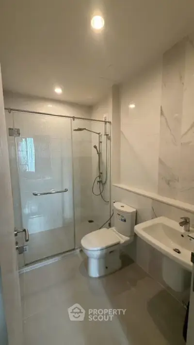 Modern bathroom with glass shower enclosure and sleek fixtures.