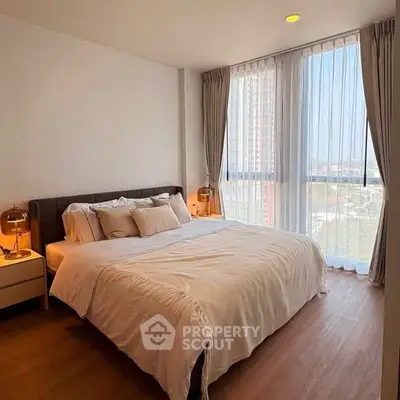 Spacious bedroom with large windows offering stunning city views and elegant decor.