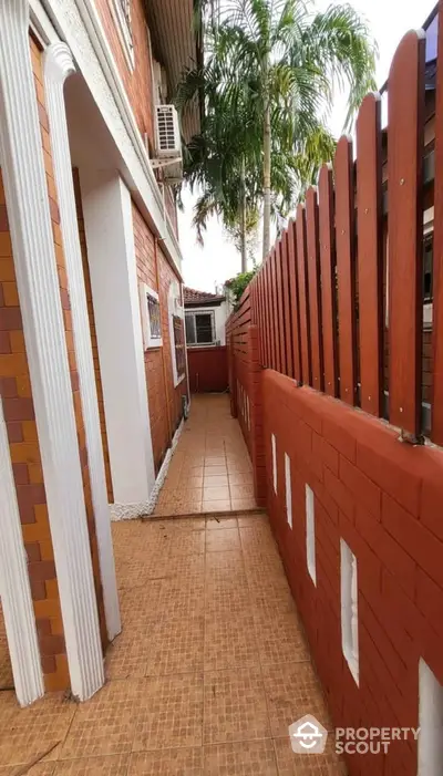 Charming exterior walkway with red brick walls and lush palm trees