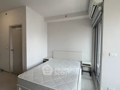 Modern minimalist bedroom with white walls and air conditioning, featuring a comfortable bed and sleek furniture.