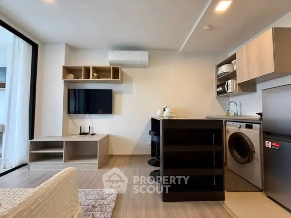 Modern open-plan living room with kitchen, featuring sleek appliances and stylish decor.