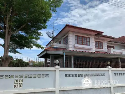 Charming two-story house with red-tiled roof and spacious fenced yard.