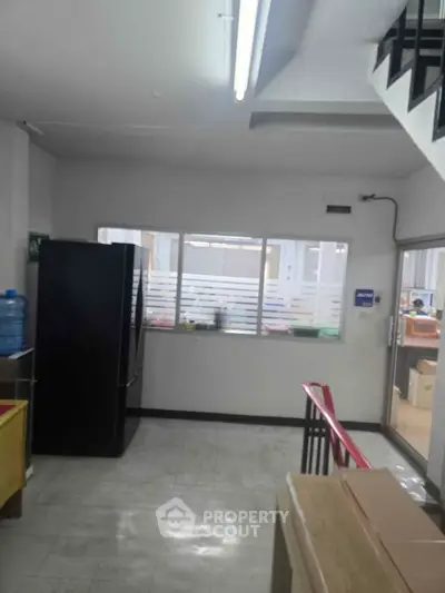 Spacious interior with modern staircase and large windows, ideal for office or commercial use.
